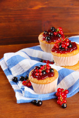 Tasty muffins with berries on wooden table