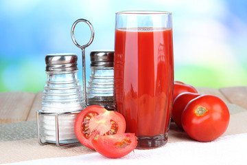 Tomato juice in glass, on wooden  table, on bright background