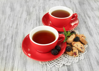 Cups of tea with cookies and blackberry on table close-up