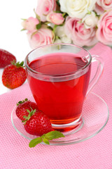 Delicious strawberry tea on table on white background