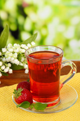 Delicious strawberry tea on table on bright background