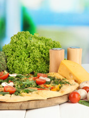 Tasty vegetarian pizza and vegetables on wooden table