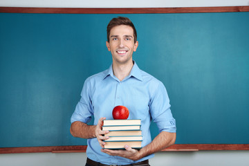 Young teacher near chalkboard in school classroom