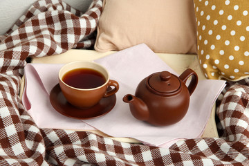 Cup and teapot on tray on bed close up