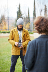 Young bearded hipster taking photo to redhead girl with TLR came