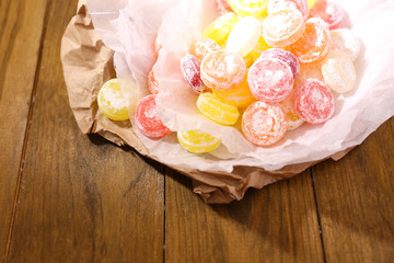Sweet  multicolor candies on paper, on wooden background
