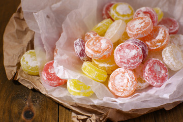 Sweet  multicolor candies on paper, on wooden background