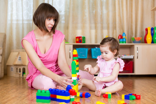 mother and her daughter play with toys at home interior