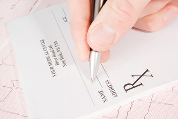 Doctor filling in empty medical prescription on ECG