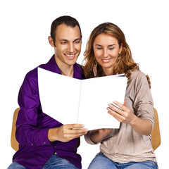 Young couple reading together a brochure with blank cover pages