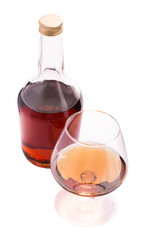 Glass and bottle of cognac isolated on white background
