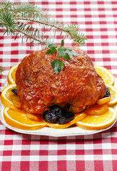 Pork served on oranges and plums. Festive dinner