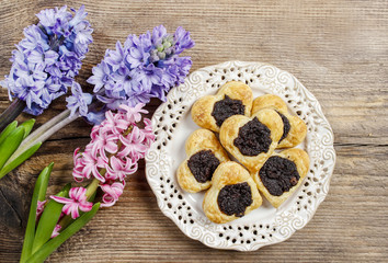 Fototapeta na wymiar Poppy seed cookies in heart shape on wooden table, hyacinth