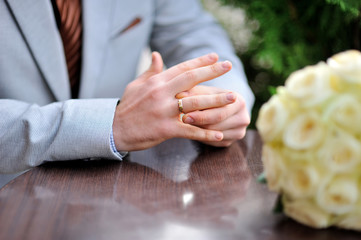 Groom is sitting at the table and twists the ring on her finger