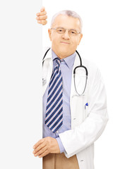 Middle aged doctor standing next to a blank panel