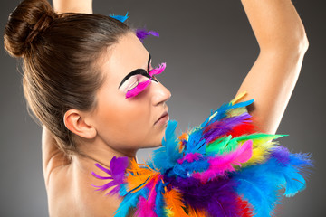 Beautiful young female model with bold make-up and feathers