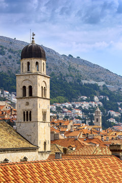 Bell tower and red-orange roof on a background of mountains and