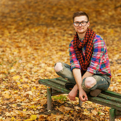 Young hipster relaxed man reading book in nature, back on tree,