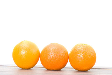 three oranges on a wooden table