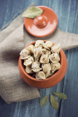 Boiled pelmeni in a pot on a wooden table, view from above