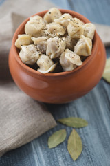 Pot of boiled pelmeni served with black pepper, close-up