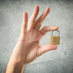 Hand holding padlock with Bitcoin symbol