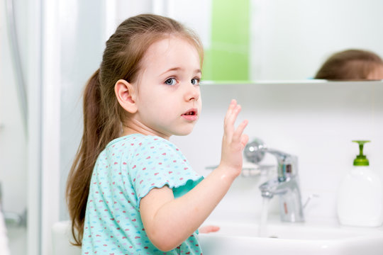 kid girl washing his face and hands in bathroom