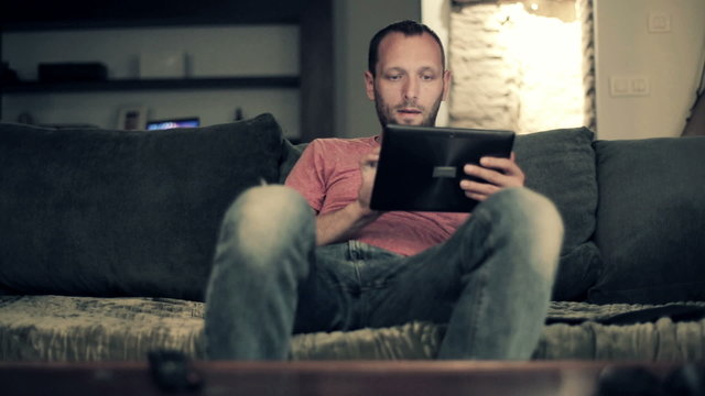 Man with tablet computer sitting on sofa at home