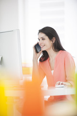 handsome woman at work in front of a computer and holding a phon