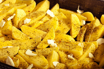 Raw peeled potatoes with spices and butter as food background