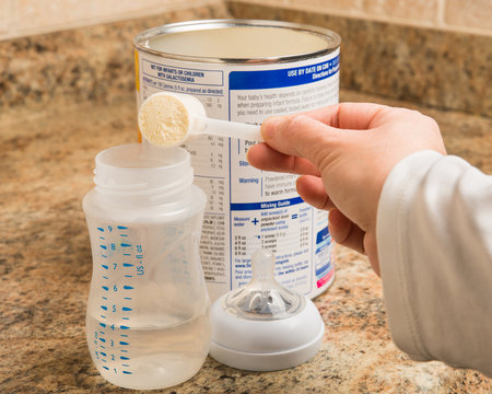 Mother preparing baby formula for infant