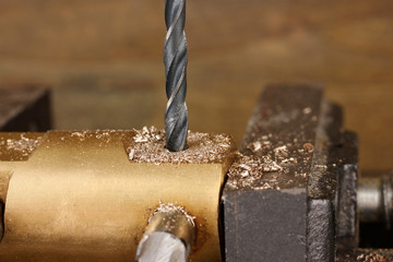 Drilling hole into metal, on wooden background