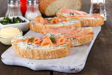 Fish sandwiches and cup of tea on cutting board on wooden table