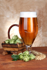 Glass of beer and hops, on wooden table