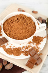 Cocoa powder in cup on napkin on wooden table