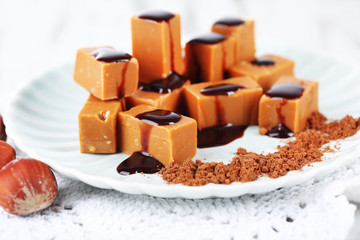 Many toffee on plate on napkin on wooden table