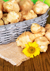 Topinambur roots in wicker basket on table close-up