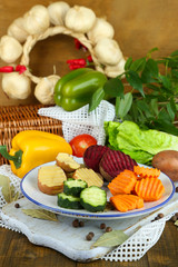 Beautiful sliced vegetables, on plate, on wooden background