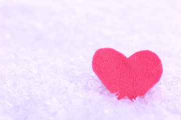 Little felt heart on snowy background