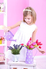 Beautiful little girl and stand with flowers on pink background