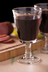 Red wine with salami and grapes on old wood table and some grape