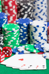 dice, four aces and chips on a green felt