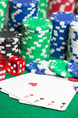 dice, four aces and colorful chips on a green felt