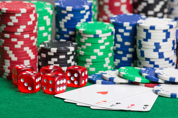 dice, four aces and colorful poker chips on a green felt