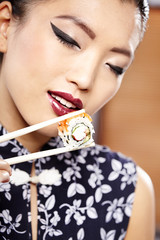 Beautiful young woman eating sushi. Shallow depth of field, focu