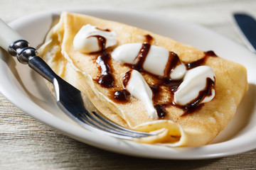 Close up of French style crepe with cream and chocolate sauce