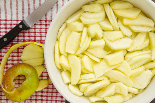 Sliced apples with peel and knife for an apple pie