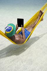 Brazilian Man Relaxing Using Tablet in Hammock on Beach