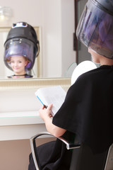 Woman reads magazine hairdressing beauty salon.