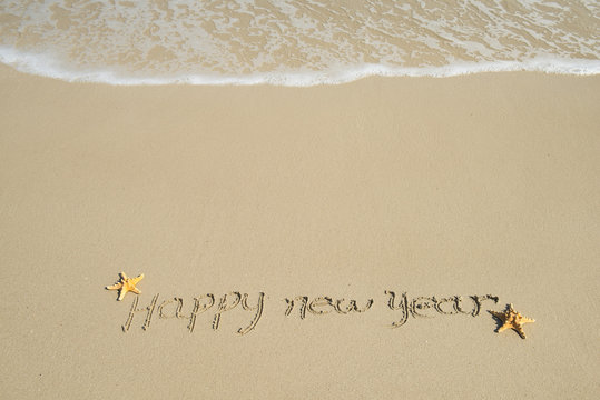 happy new year written in the sand